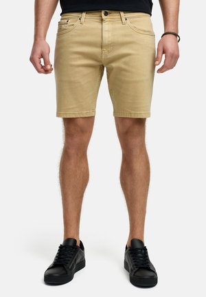 Knielange beige denimshorts med et klassisk fem-lomme design og lige pasform. Kombinationen med sorte lavtop sneakers.
