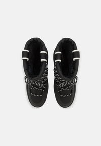 Bottes d'hiver noires avec collets rembourrés, lacets à rayures blanches noués en nœuds, et accents de bandes réfléchissantes blanches sur un fond blanc.