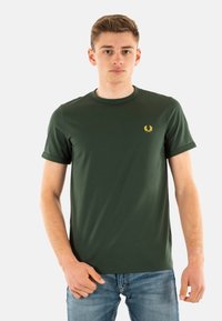 Camiseta verde de manga corta hecha de algodón, con un cuello redondo y un pequeño logo amarillo en el lado izquierdo del pecho. Textura suave.