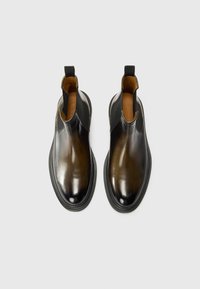 Bottes Chelsea en cuir avec une finition dégradée du marron foncé au noir. Présente des panneaux latéraux élastiques et un design à bout rond.