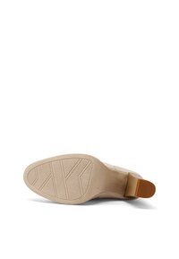 Scarpa con tacco beige, soffice e con suola in gomma testurizzata, tacco leggermente curvato e tomaia in pelle liscia. Dettagli trasparenti sulla suola.