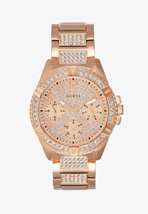 Montre-bracelet Guess en or rose avec lunette, cadran et maillons de bracelet ornés de cristaux, comprenant trois sous-cadrans pour 24 heures, date et jour.