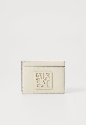 Beige Kartenhalter aus strukturiertem Synthetikmaterial, mit hervorgehobenem Logo-Plakette und gesteppten Details entlang der Kanten.