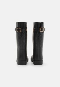 Des bottes de pluie en caoutchouc noir avec un motif texturé, deux boucles réglables et une finition lisse sur la tige et le talon.