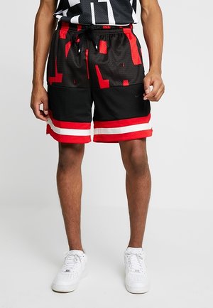 Pantalones cortos deportivos negros con detalles en rojo, con textura de malla, cinturilla elástica y dobladillos con rayas blancas. Logo de Nike visible.