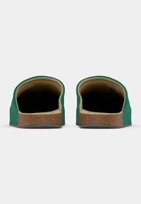 Zöld bebújós cipők texturált felsőrésszel, bézs béléssel és parafa talppal. A hátulnézet sima kontúrokat és nincs díszítő fém alkatrész.