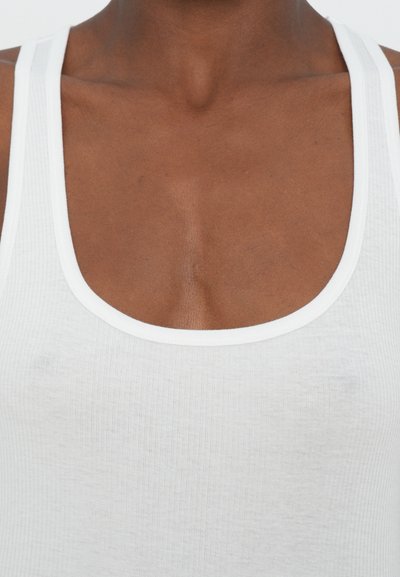 Biała prążkowana tank top z kwadratowym dekoltem i wąskimi ramiączkami. Materiał wydaje się miękki i elastyczny, z minimalnymi widocznymi detalami tekstury.
