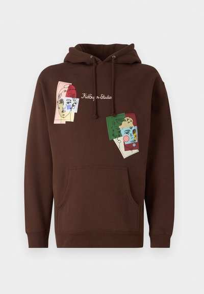 Brun hettegenser med frontlomme og snor i hetten, med fargerike kunstneriske ansiktsillustrasjoner og teksten "Kidboy Studio".