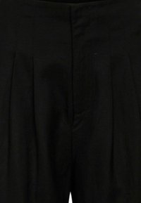 Zwarte geplooide broek met een soepele textuur. Heeft een aansluitende taille en zakken, ontworpen in een klassieke, op maat gemaakte stijl.