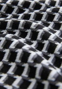 Black and white patterned fabric with geometric shapes, textured weave, soft appearance, and a slight stretch.