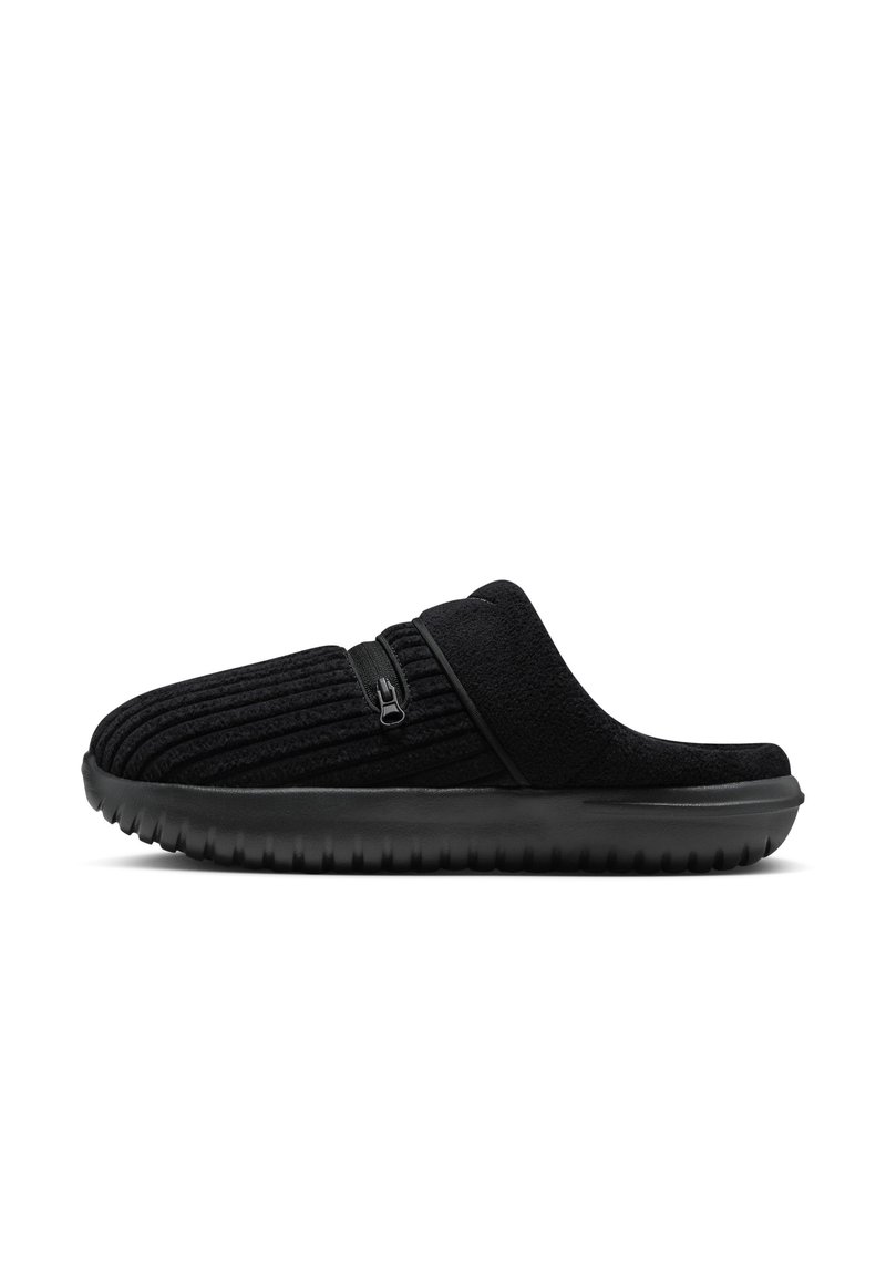 Zapatillas negras con una textura acanalada, parte superior de felpa y un detalle en cremallera negra en el lateral. Suela de goma negra gruesa para mayor tracción.