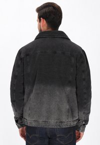 Giacca di denim con gradiente dal nero al grigio. Presenta un colletto a punta, maniche lunghe e polsini con bottone. Tessuto con effetto usurato.