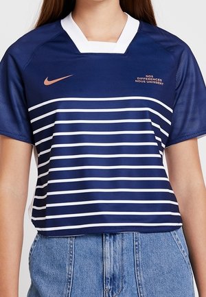 T-shirt de sport Nike rayé bleu marine et blanc à manches courtes, swoosh or rose, avec le texte français "NOS DIFFERENCES NOUS UNISSENT."