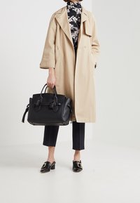 Beige trench coat, black handbag, black pants, and black mules with a square buckle. Smooth fabric with a tailored fit and open design.