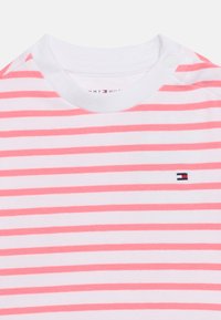 Λευκό και ροζ ριγωτό παιδικό πουκάμισο με στρογγυλή γραμμή λαιμού, κουμπιά κλικ στον ώμο και μικρό λογότυπο Tommy Hilfiger στο στήθος.