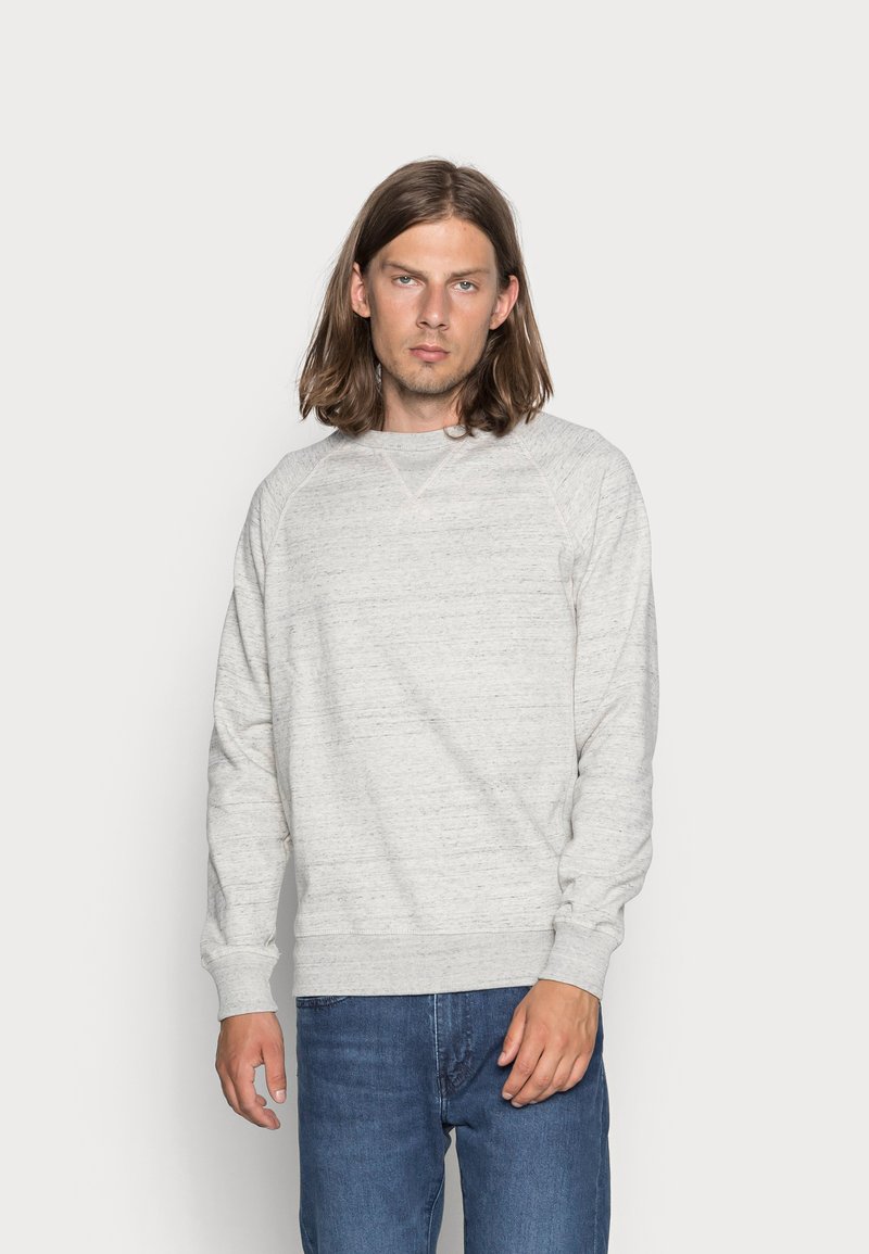 Lichtgrijze sweatshirt met een gestructureerde afwerking, raglanmouwen en ribgebreide cuffs. Gecombineerd met blauwe denim jeans. Eenvoudig, casual ontwerp.