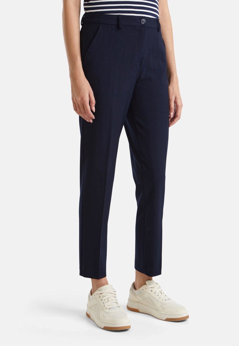 Námořnické kalhoty z hladké látky, se střihkem na tělo, bočními kapsami a zapínáním na knoflík. V kombinaci s bílými teniskami.