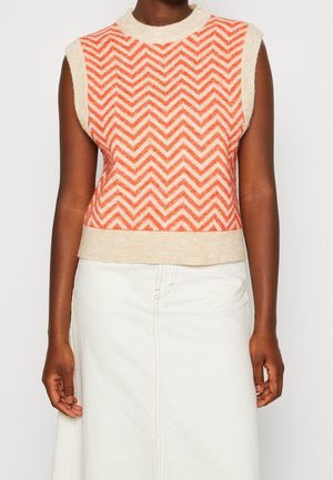 Un pull sans manches présentant un motif en chevrons rouge et crème avec un ourlet beige. Fabriqué en tissu texturé, il a un col haut.