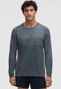 Dlhý rukáv košeľa tmavosivej farby s textúrovaným vzorom, s raglánovými rukávmi a okrúhlym výstrihom. Hladká tkanina, voľný strih.