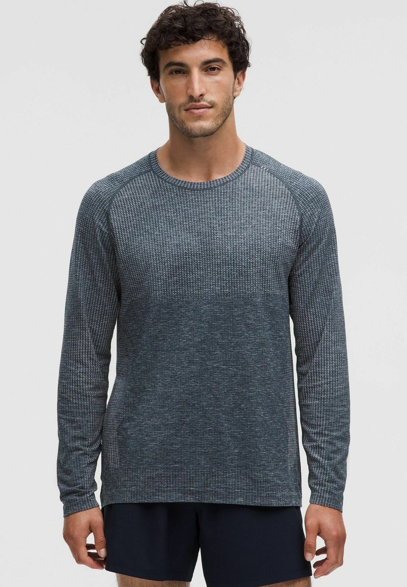 Dlhý rukáv košeľa tmavosivej farby s textúrovaným vzorom, s raglánovými rukávmi a okrúhlym výstrihom. Hladká tkanina, voľný strih.