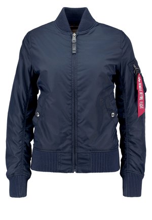 Veste bomber bleu marine en tissu lisse et léger. Présente des poignets et un ourlet côtelés, une fermeture à glissière et une étiquette rouge 'Retirez avant le vol' sur la manche.