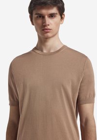Lysbrun, kortærmet t-shirt med rund hals, der har en glat tekstur og ribbede mansjetter, med en afslappet pasform og minimalistisk design.