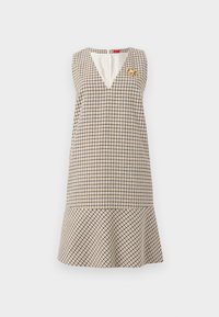 Φόρεμα χωρίς μανίκια σε γραμμή Α με μπεζ και μαύρο καρό μοτίβο, λαιμόκοψη σε σχήμα V, φαρδιά βάση και χρυσό μπρότσο πεταλούδας στο αριστερό στήθος.