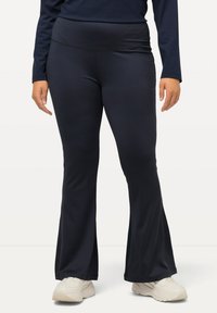 Pantaloni yoga blu navy con fondo svasato, realizzati in un tessuto liscio ed elasticizzato. Presentano un ampio e comodo elastico in vita per un supporto aggiuntivo.