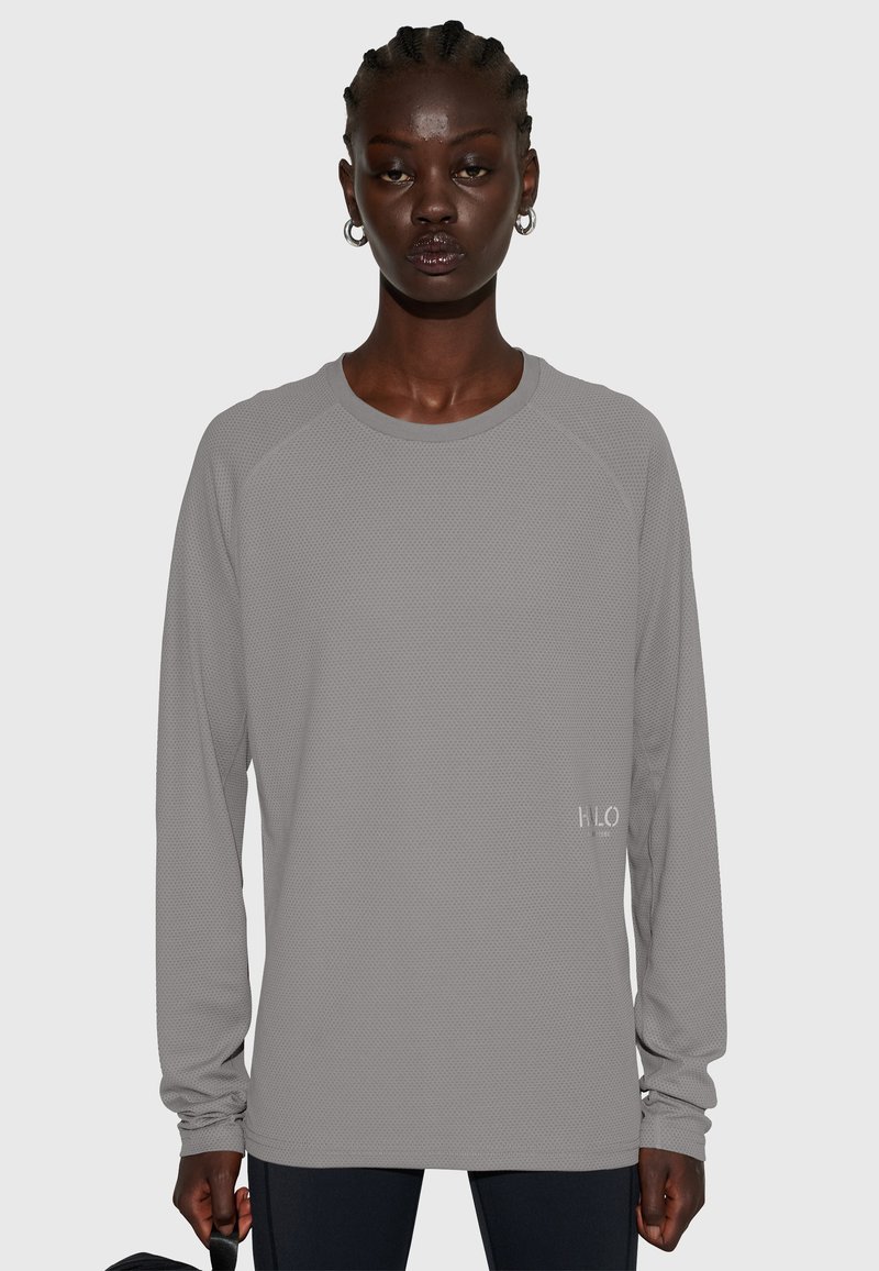 Långärmad, ljusgrå träningsöverdel med strukturerad design och raglanärmar. Har en liten "H.L.O"-logga på framsidans nedre vänstra del.