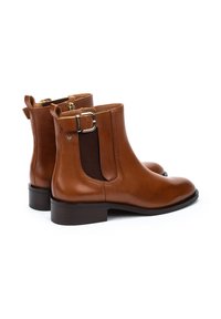 Botas de tobillo de cuero marrón con paneles laterales elásticos, acentos de hebilla, punteras redondeadas y un tacón bajo y apilado. Textura suave con acabado pulido.