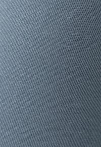 Tecido azul elástico com uma textura canelada fina, cor uniforme com um brilho sutil, adequado para peças de vestuário como blusas ou leggings.