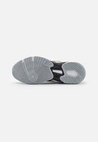 Black and grey athletic shoe sole features textured rubber, a circular pattern at the heel, and ridges for traction.
