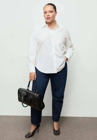 Biela košeľa na gombíky, tmavé denimové nohavice, čierna kabelka a hnedé lodičky na vysokom opätku. Jednoduchý dizajn s hladkou textúrou a klasickým strihom.