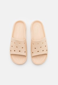Beige instapsandalen van zacht, geperforeerd materiaal met een gladde textuur en een gevormde voetbed, met een breed bandontwerp.