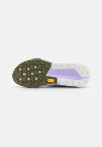 La semelle de la chaussure de trail présente un mélange de caoutchouc violet clair, vert olive et blanc. Un motif de crampons notable pour une meilleure adhérence et durabilité.