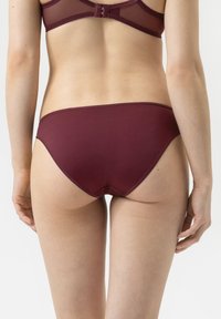 Culotte femme bourgogne avec une texture lisse, dotée d'une bordure en dentelle à l'arrière et d'un design à taille basse.