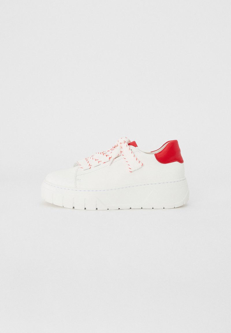 Sneaker blanc avec une épaisse semelle blanche et un talon rouge, présentant un matériau texturé, des lacets rouges vifs avec des rayures blanches, et un design minimaliste.