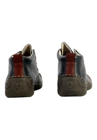 Bottes en cuir montant jusqu'à la cheville avec un extérieur bleu foncé, des accents rouges, des coutures latérales et des semelles en caoutchouc texturées. Elles ont une languette à l'arrière.