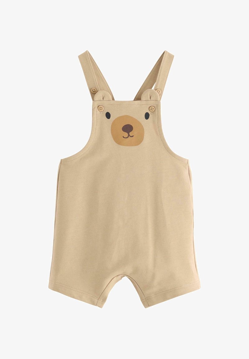 Bear-themed beige overalls with short legs, featuring a rounded bear face print and bear ear details on the shoulder straps. Cotton material.