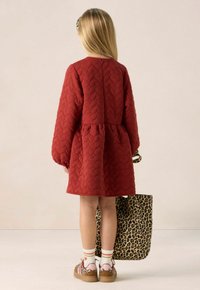 Rode geborduurde jurk met lange mouwen en een gathered taille. Gepaarde met een tas met luipaardprint en patronen schoenen met dikke zolen.