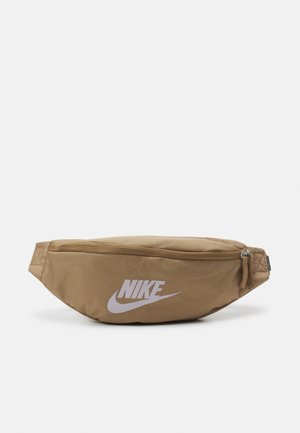 Hellbraune Nike-Gürteltasche mit oberem Reißverschluss und weißem Nike-Logo vorne, vor einfarbigem Hintergrund dargestellt.