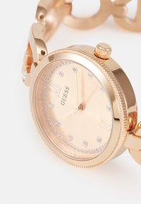 Roségoldene Uhr mit rundem Gehäuse, strukturiertem Gehäuseboden und diamantähnlichen Akzenten auf dem Zifferblatt. Verfügt über ein Gliederarmband und minimalistische Stundenmarkierungen.