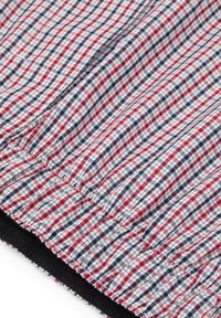 Tkany materiał w czerwono-białą granatową kratę; ma gładką teksturę i zmarszczoną krawędź z solidnym czarnym wykończeniem.