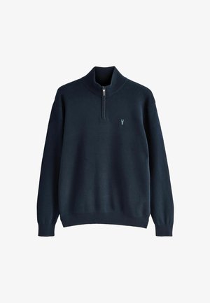 Mørkeblå strikket pullover med en kvart lynlås krave og en lille lyseblå hjortehovedbroderi på venstre bryst.