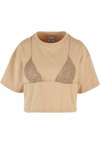 Avskåret, beige bomulls t-skjorte med et minimalistisk grafisk design av en bikini overdel i en mørkere nyanse. Korte ermer og rund hals.