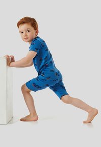 Blaues Kurzarmhemd und Shorts-Set mit bunten grafischen Mustern. Weicher Stoff, figurbetontes Design und entspannte Passform, geeignet für Kinder.