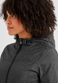Gray jacket with a textured pattern, featuring a zippered front, hood, and adjustable hardware for fit. Material appears lightweight and smooth.