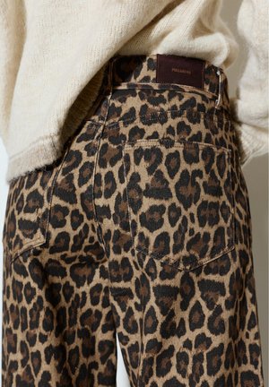 Hlače z leopardjim vzorcem z zadnjim žepom in rjavo oznako Pull&Bear, kombinirane z ohlapnim bež pletenim puloverjem.