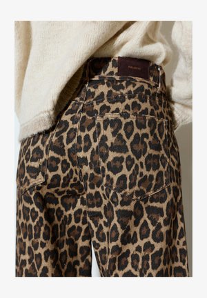 Hlače z leopardjim vzorcem z zadnjim žepom in rjavo oznako Pull&Bear, kombinirane z ohlapnim bež pletenim puloverjem.