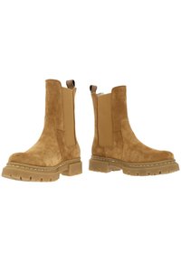 Světle hnědé semišové kotníkové boty s elastickými bočními panely, robustními gumovými podrážkami a zadními poutky pro snadné obouvání. Kontrastní šití je viditelné na podrážce.